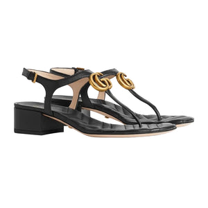 Black sandals with gold accents on a light gray background