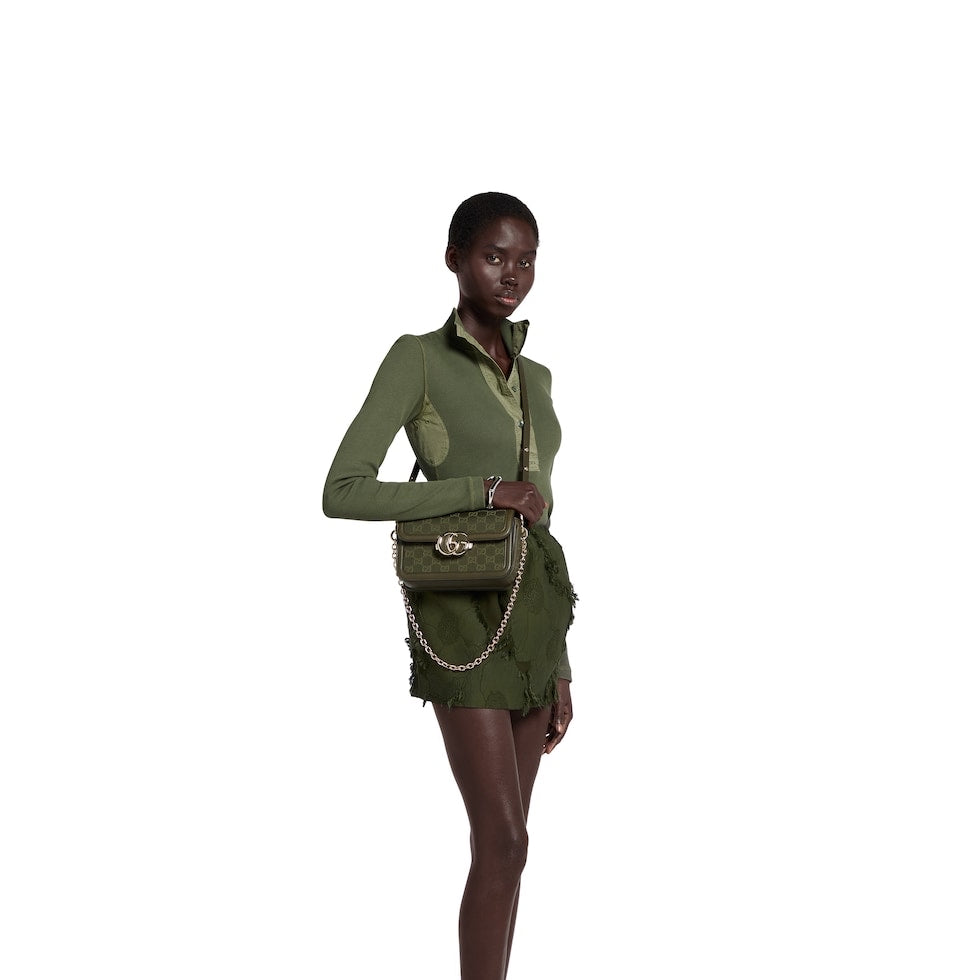 Person wearing a green outfit with a matching bag on a white background