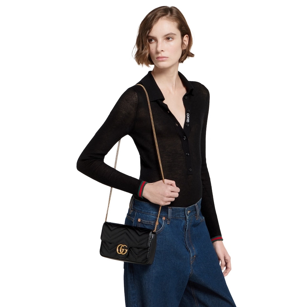 Woman holding a black handbag with a gold chain strap on a white background