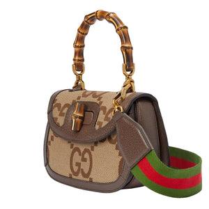 Designer handbag with bamboo handle and matching belt on a light gray background