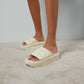 Beige platform sandals worn on a neutral background
