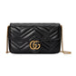 Black quilted handbag with gold chain and Gucci logo on a light gray background