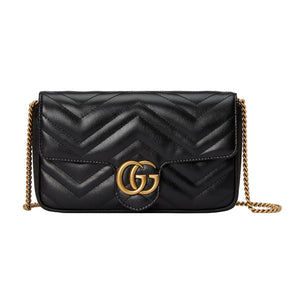 Black quilted handbag with gold chain and Gucci logo on a light gray background