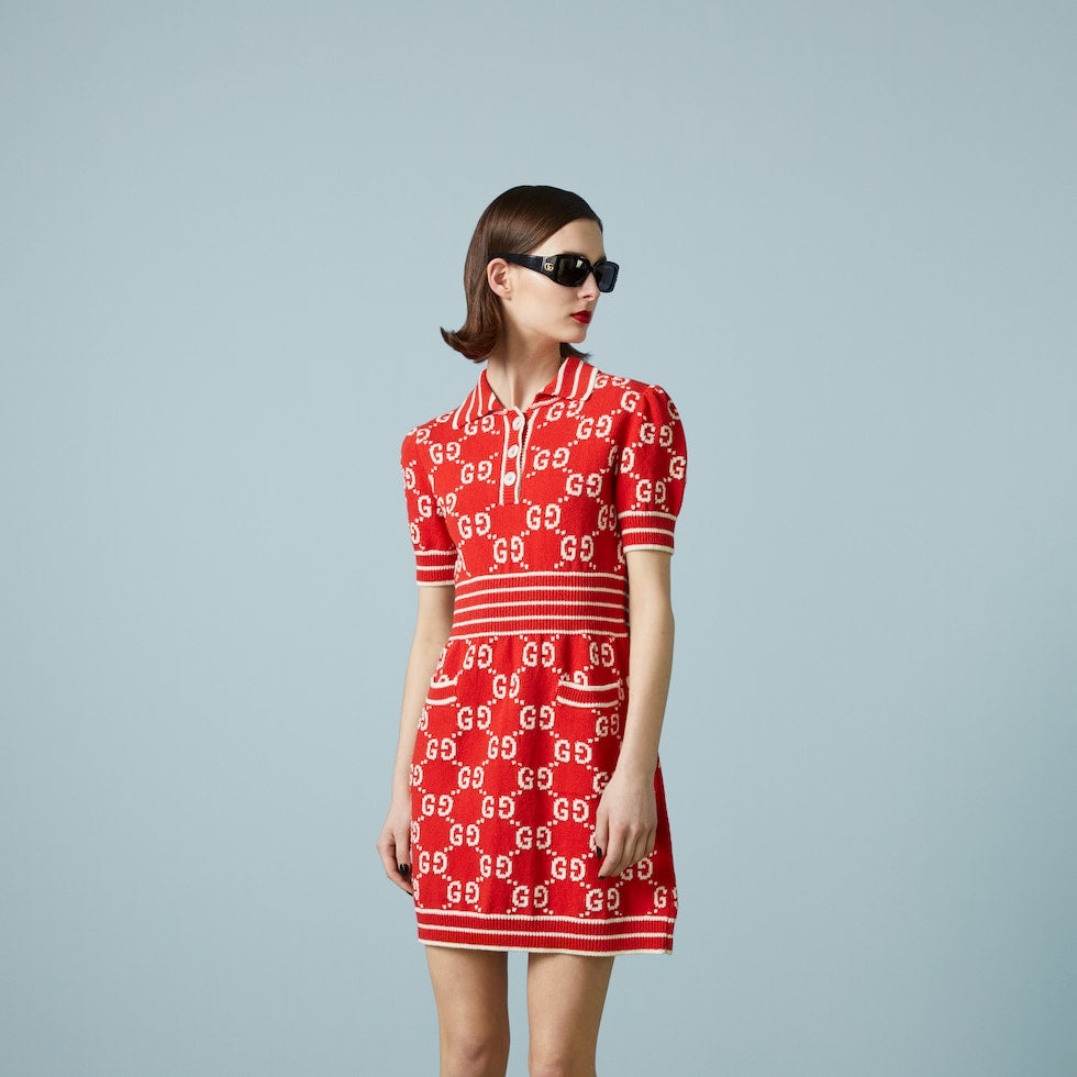 Woman wearing a red patterned dress with sunglasses on a gray background