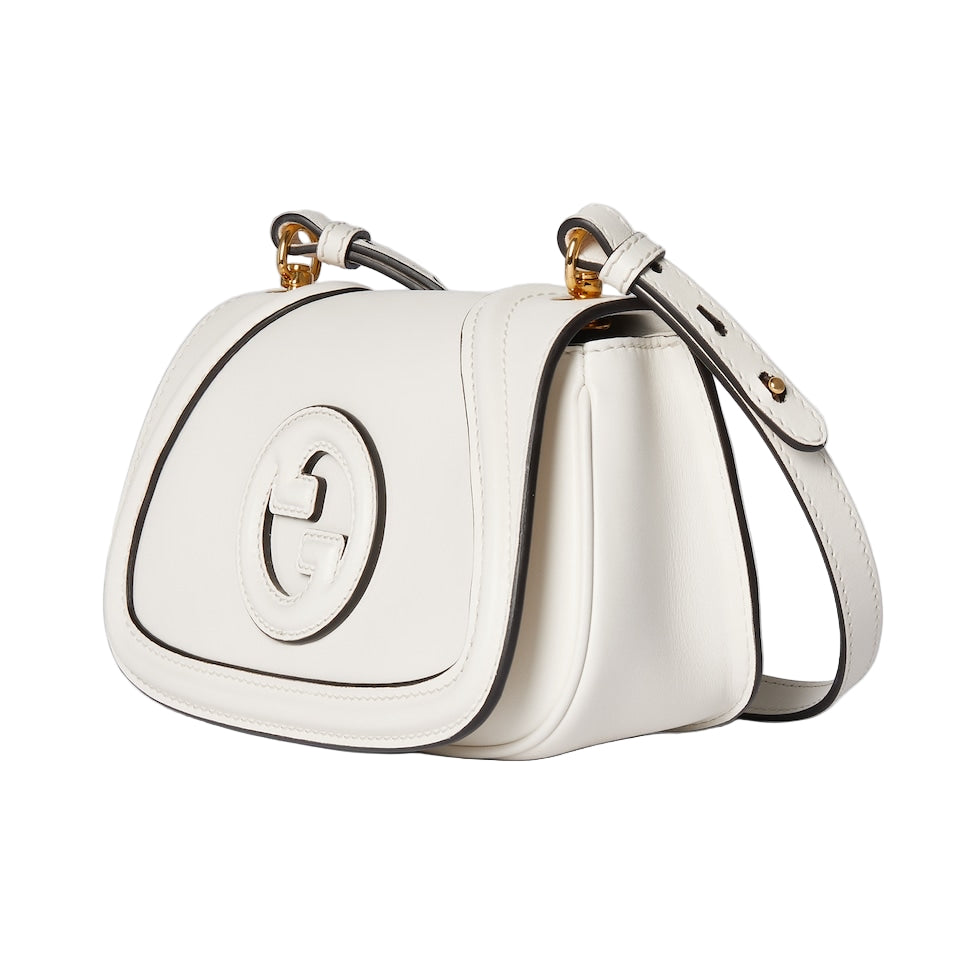 White handbag with gold accents on a light gray background