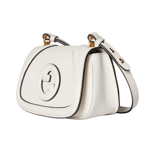 White handbag with gold accents on a light gray background