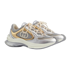 Silver and gold sneakers with a brand logo on a light gray background