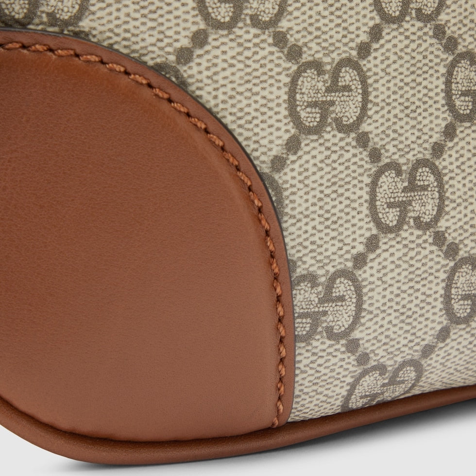 Close-up of a Gucci handbag with brown leather trim on a light gray background