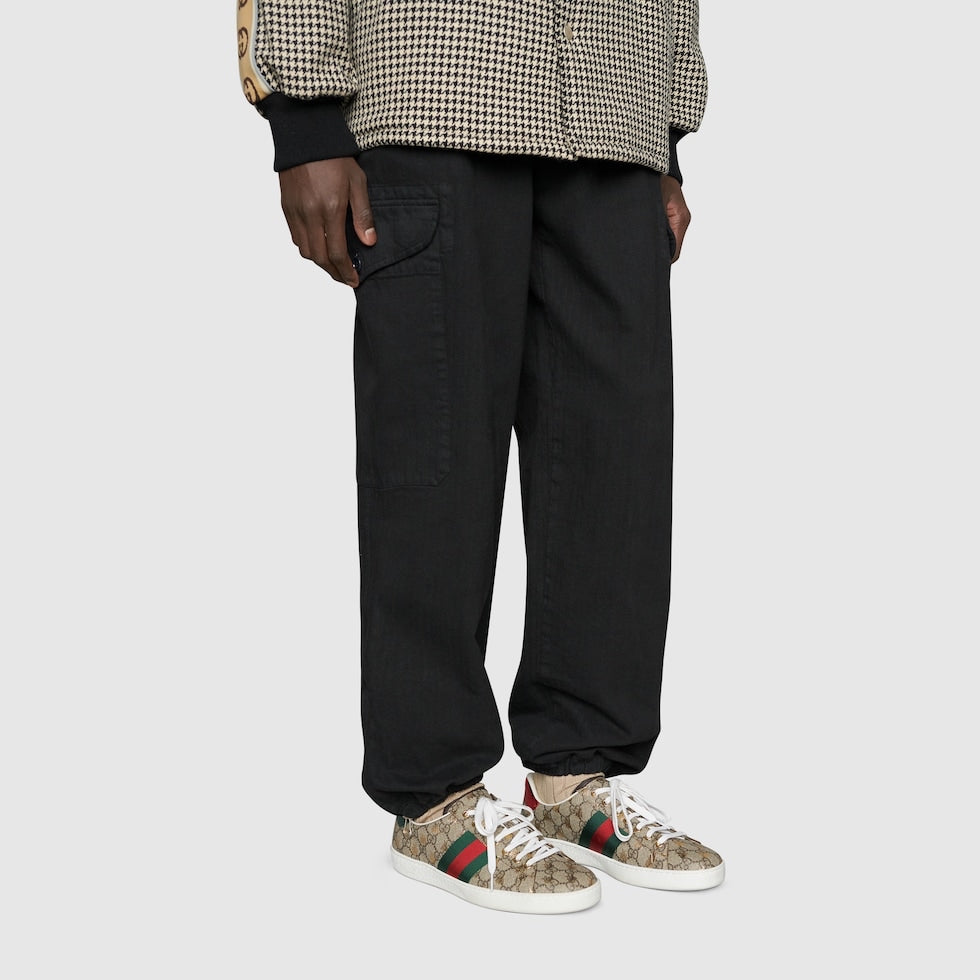 Person wearing black pants and patterned shoes on a light gray background