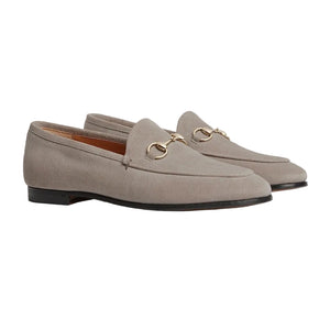 Pair of beige loafers with gold buckles on a light gray background