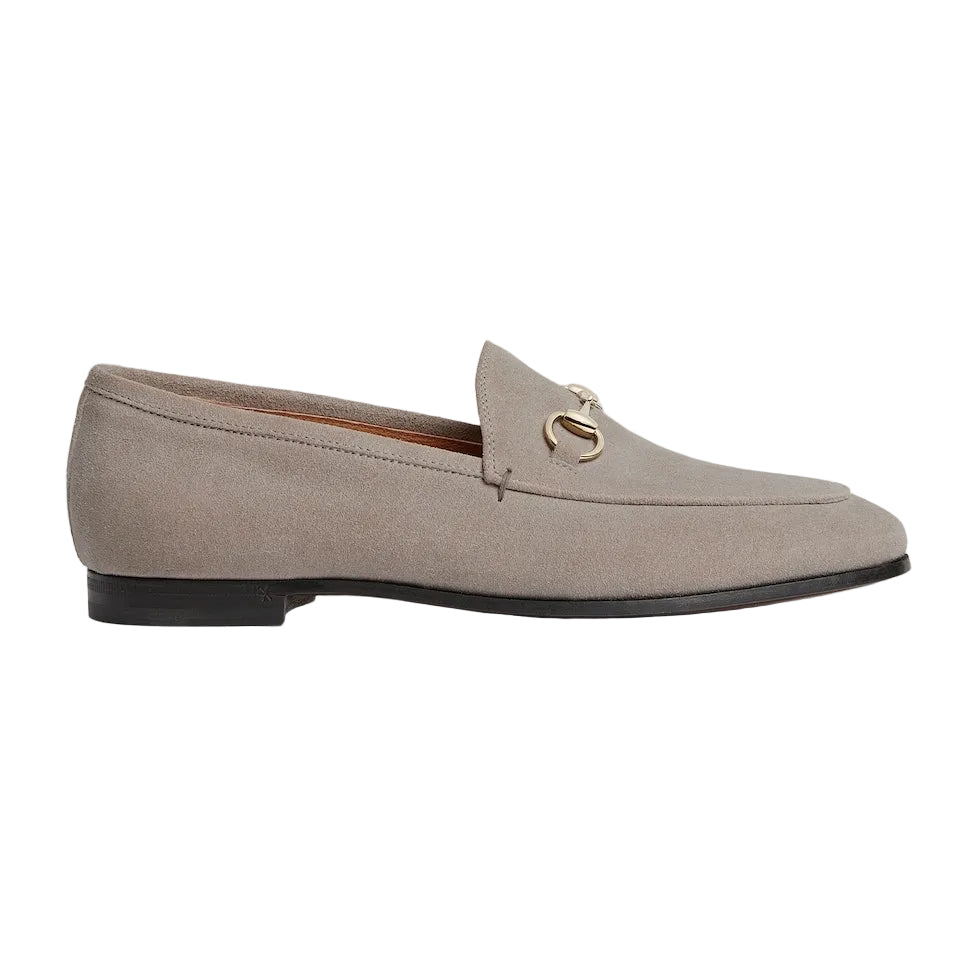 Beige loafer shoe with a gold buckle on a white background