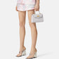 Person wearing a patterned skirt and holding a handbag on a white background