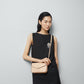 Woman holding a beige handbag against a plain background
