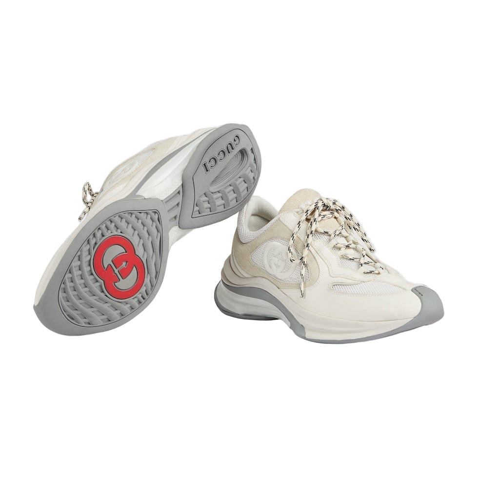 White sneakers with gray soles and a red logo on a light gray background