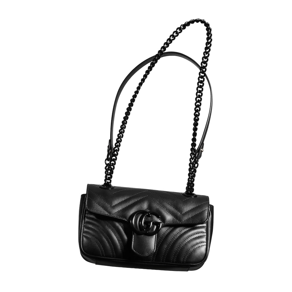 Black quilted handbag with chain strap on a light gray background