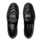 Pair of black Gucci loafers with gold logo on a light gray background