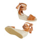 Pair of tan wedge sandals with espadrille sole on a light gray background