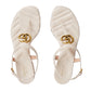 Pair of beige quilted sandals with gold Gucci logo on a light gray background