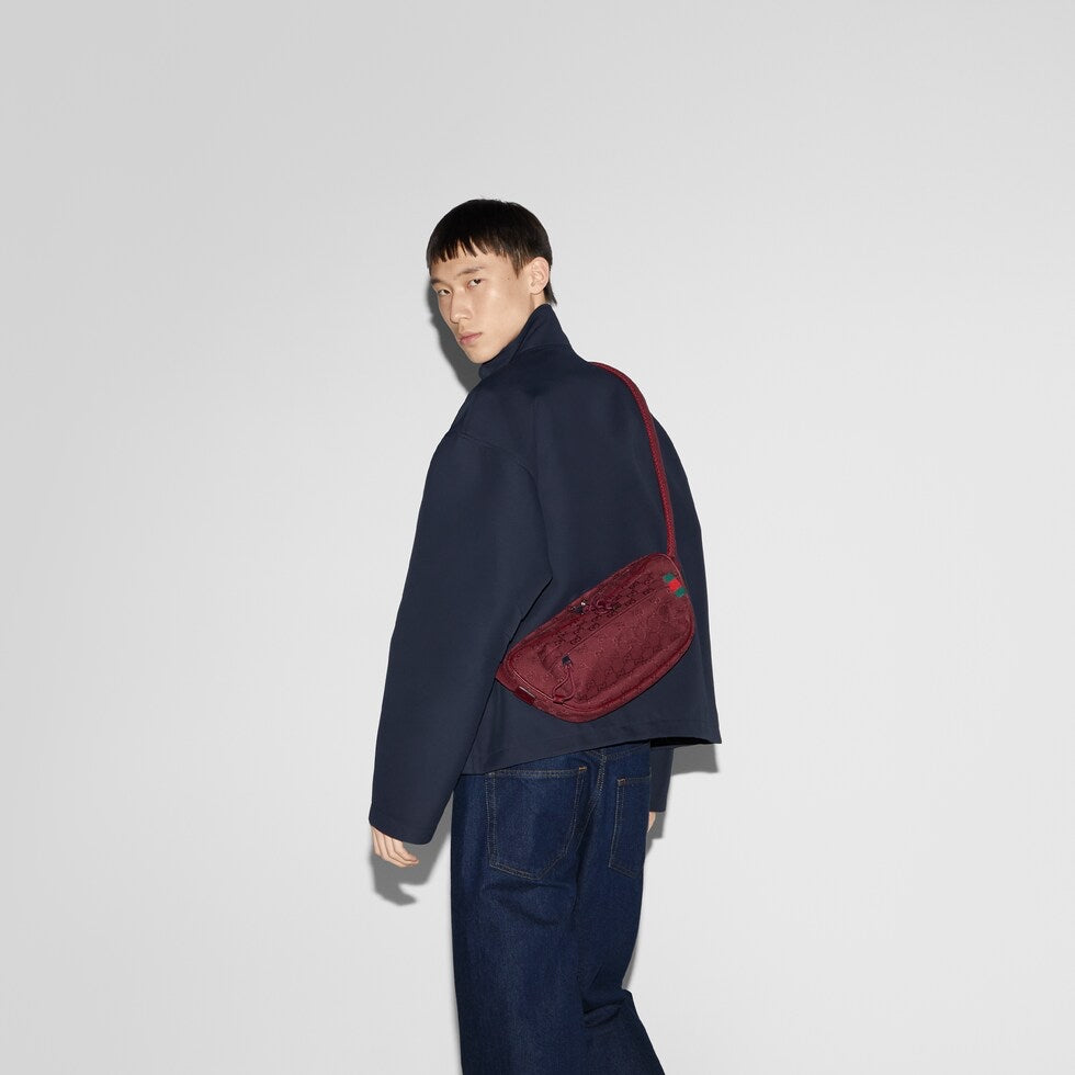 Person wearing a dark blue outfit with a red bag on a white background