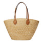Woven straw tote bag with brown leather handles on a light gray background