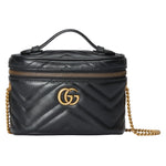 Black quilted Gucci handbag with gold chain and logo on a light gray background