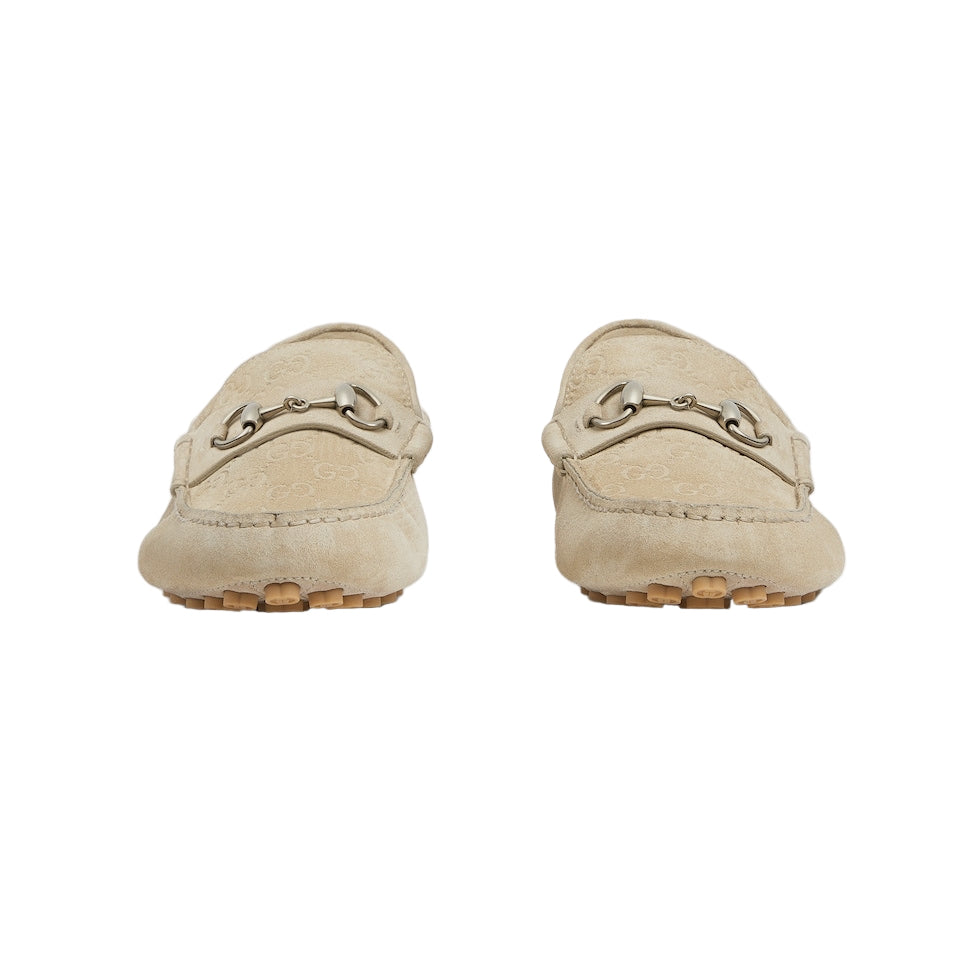 Pair of beige loafers with a decorative buckle on a light gray background