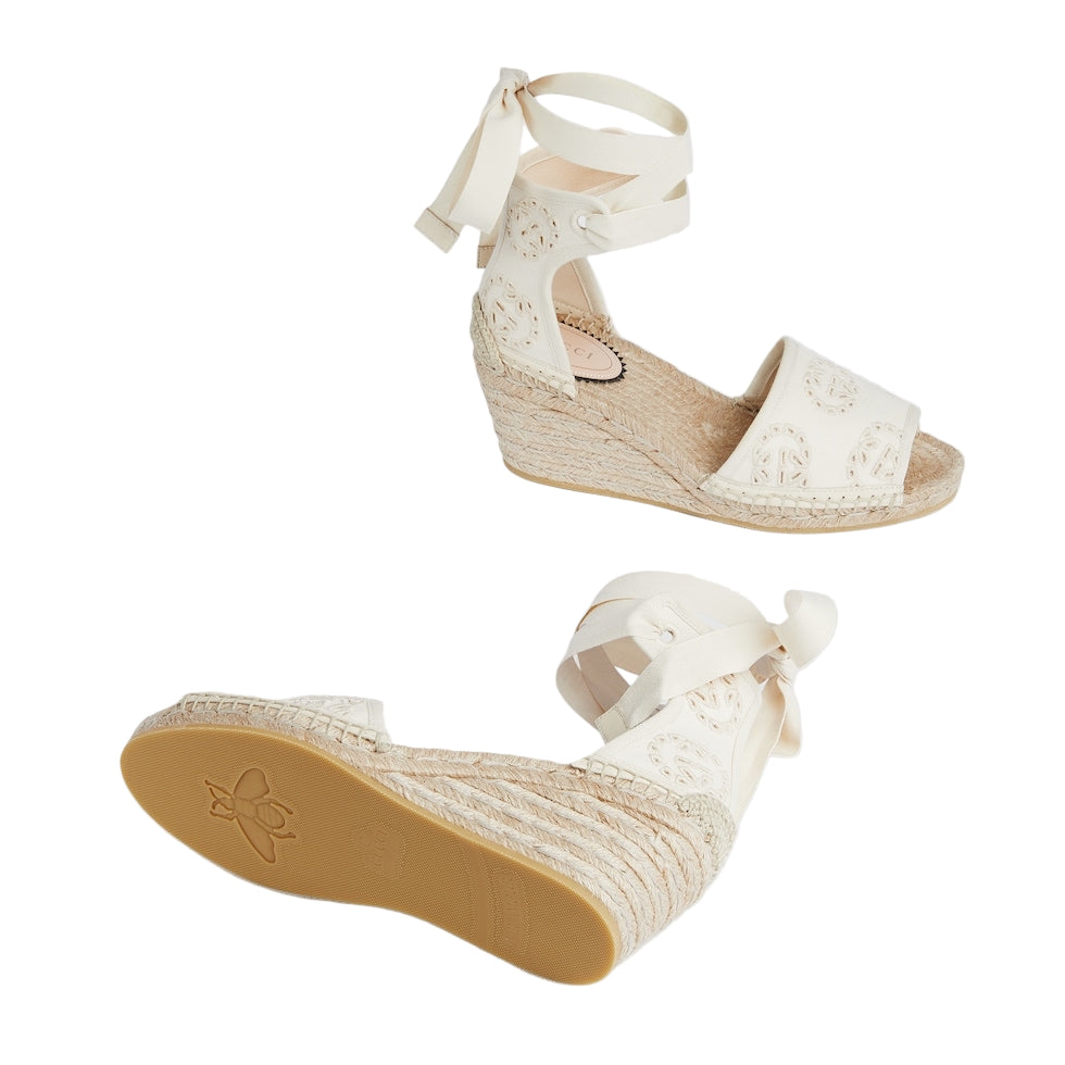 White wedge sandals with espadrille sole on a light gray background