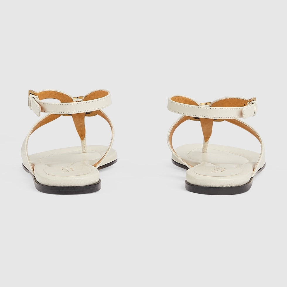 Pair of white sandals with brown straps on a light gray background
