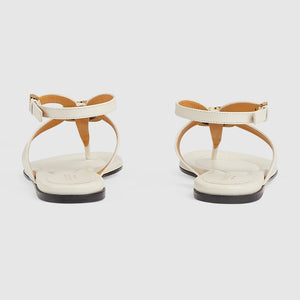 Pair of white sandals with brown straps on a light gray background