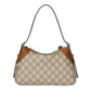 Designer handbag with patterned surface and brown accents on a light gray background