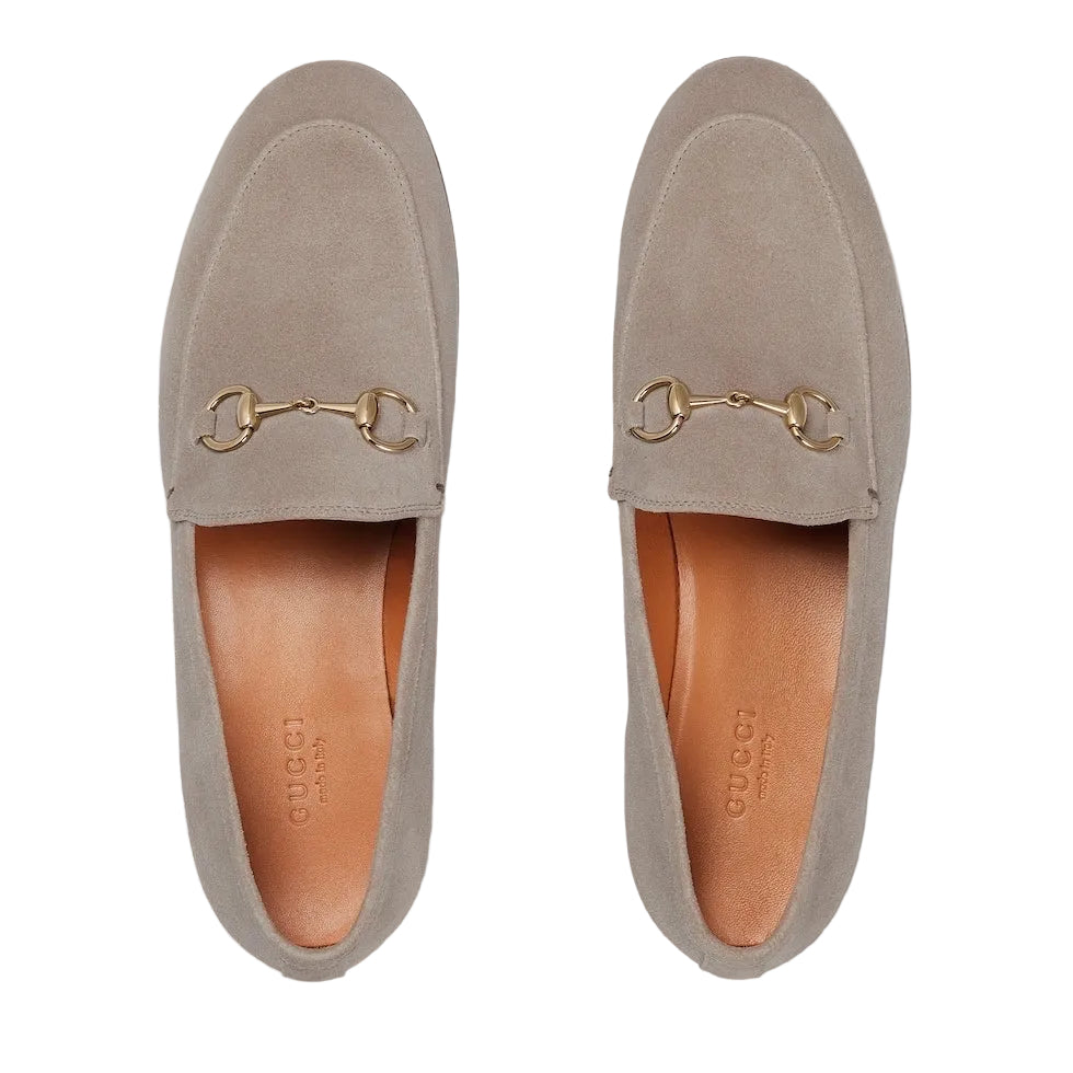 Pair of beige loafers with gold accents on a light gray background
