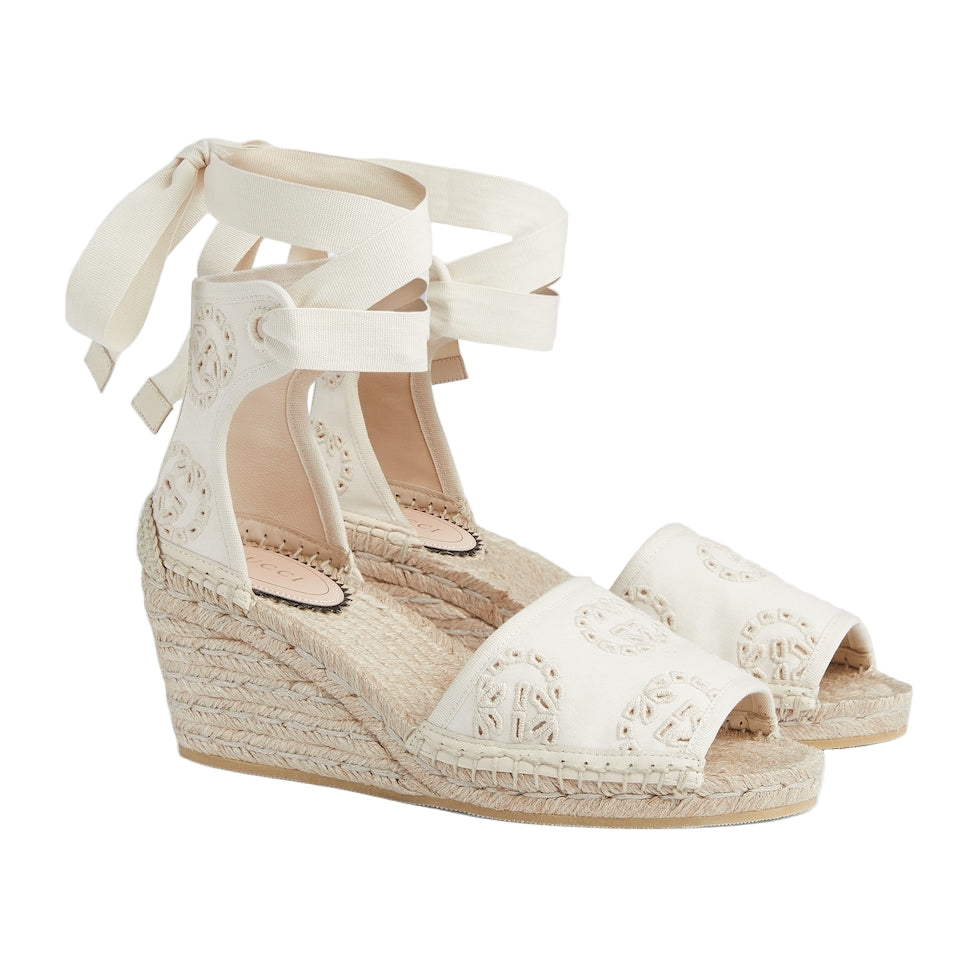 White wedge sandals with espadrille sole on a light gray background