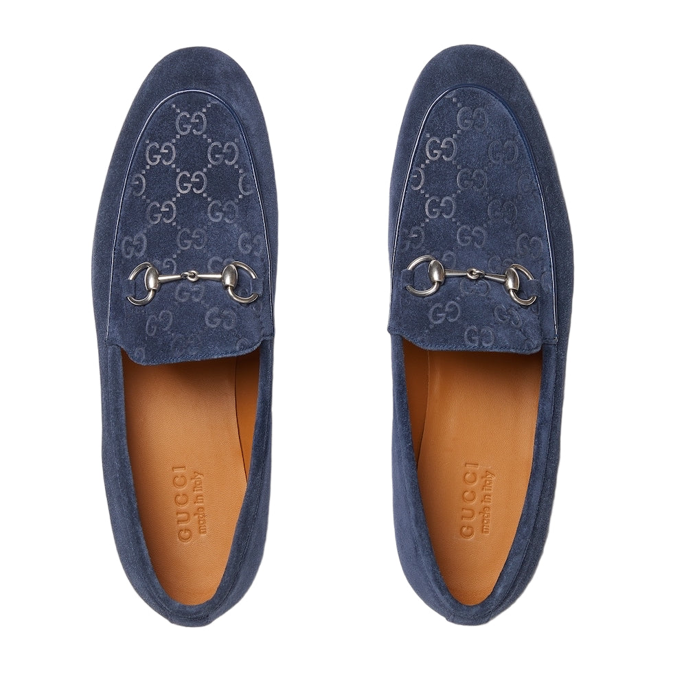 Pair of blue suede loafers with Gucci logo on a light gray background