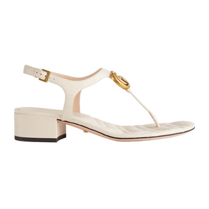 Beige sandal with gold buckle on a light gray background