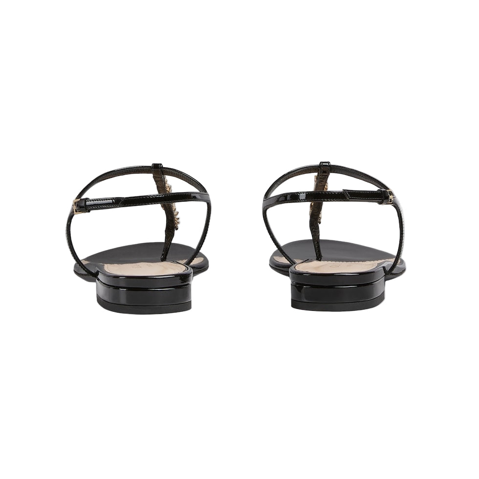 Pair of black sandals with thin straps on a light gray background