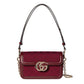 Red handbag with gold chain and logo on a light gray background