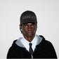 Person wearing a black Gucci cap and black hoodie with white collar on a white background