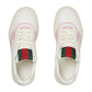 White sneakers with pink accents and green and red ribbons on a light gray background