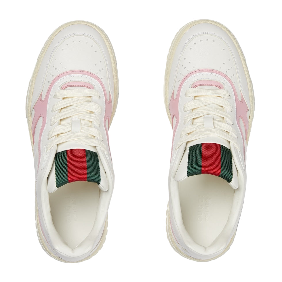 White sneakers with pink accents and green and red ribbons on a light gray background