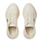 Pair of cream-colored sneakers with blue accents on a white background