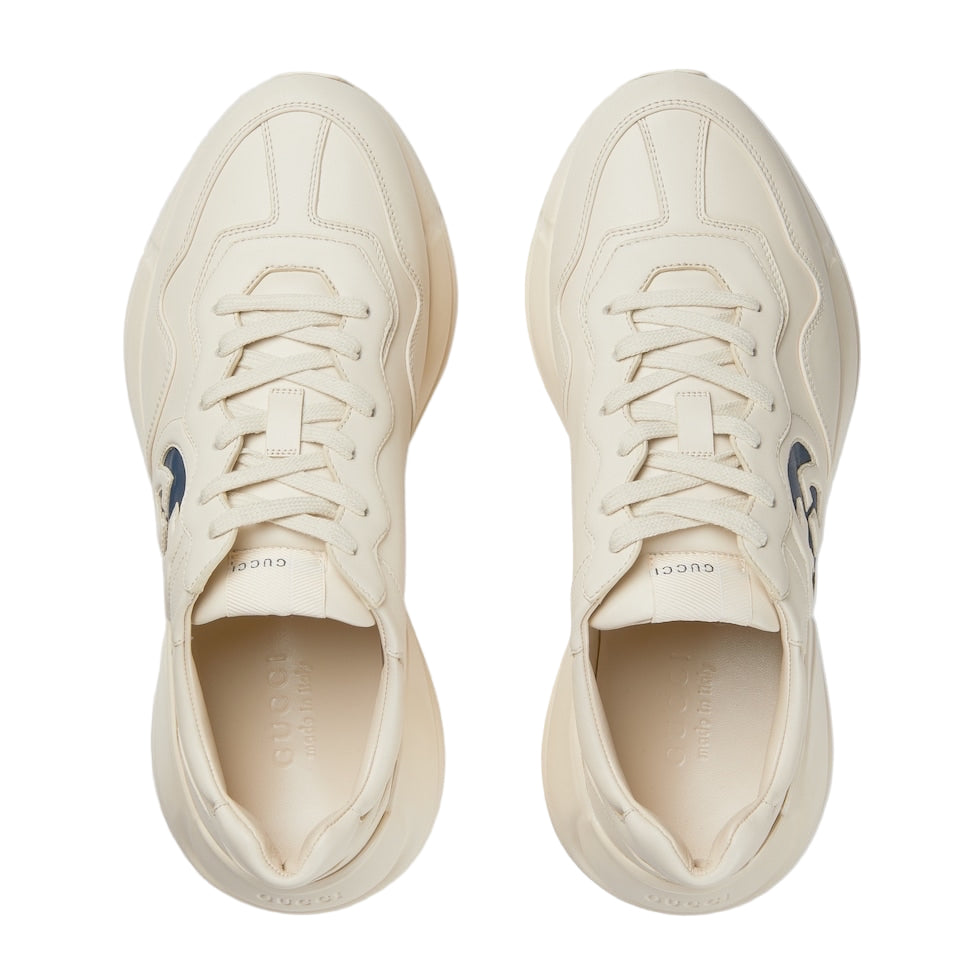 Pair of cream-colored sneakers with blue accents on a white background