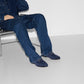 Person wearing blue jeans and shoes sitting on a chair with a white background