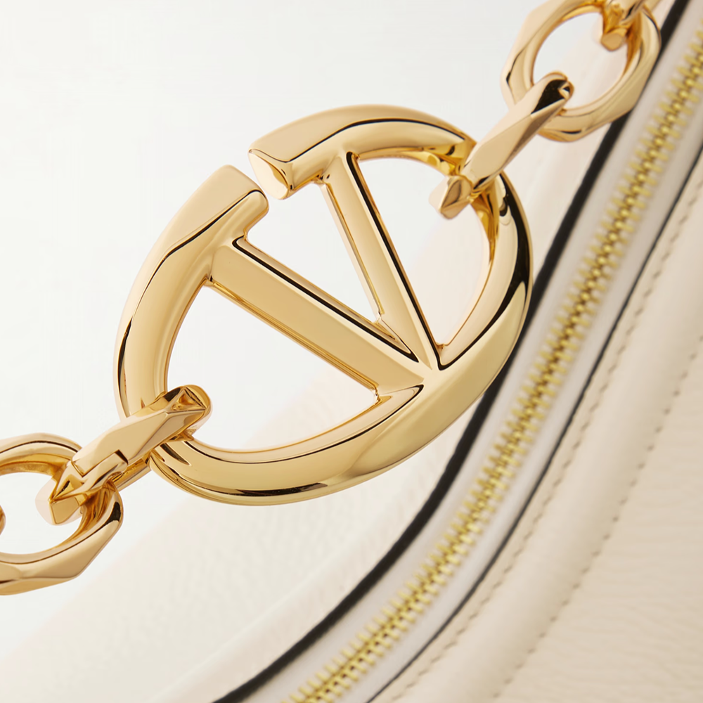 Close-up of a gold chain with a logo on a beige background