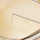 Close-up of a beige handbag with gold zipper and Valentino logo.