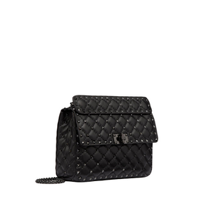 Black quilted handbag with chain detail on a light gray background