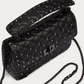 Black studded handbag with chain strap on a light gray background