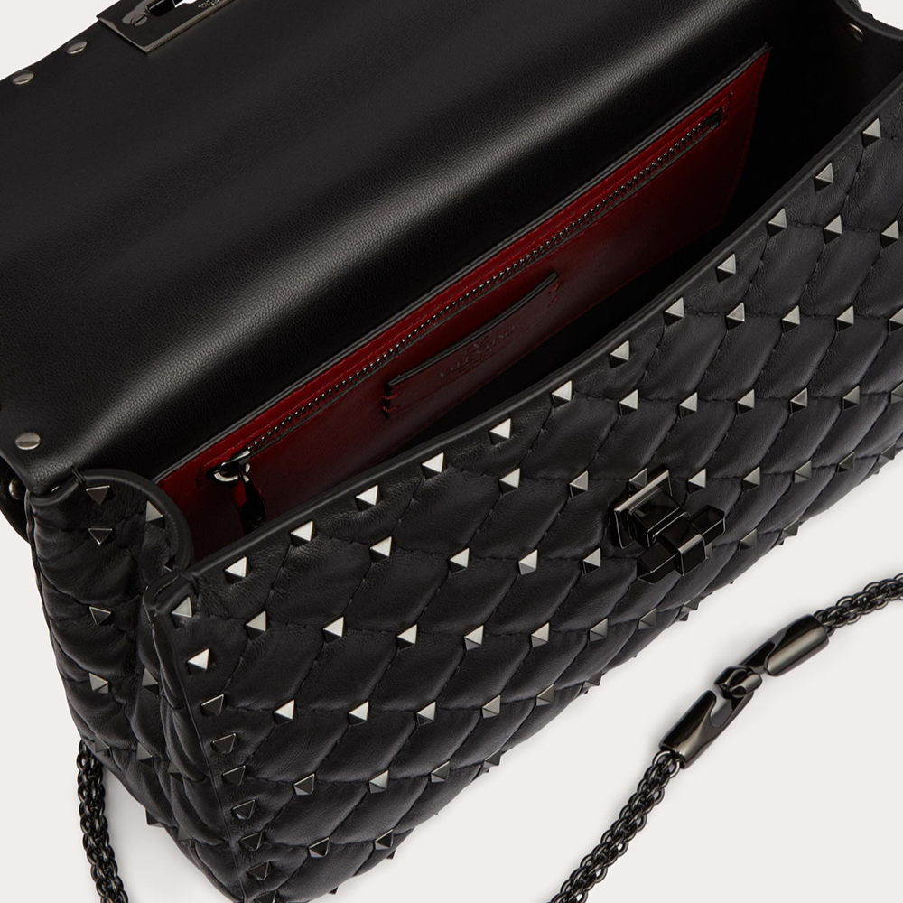 Black studded handbag with a chain strap on a white background