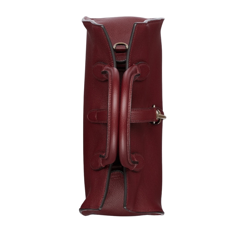 Red leather duffel bag with gold buckle on a light gray background