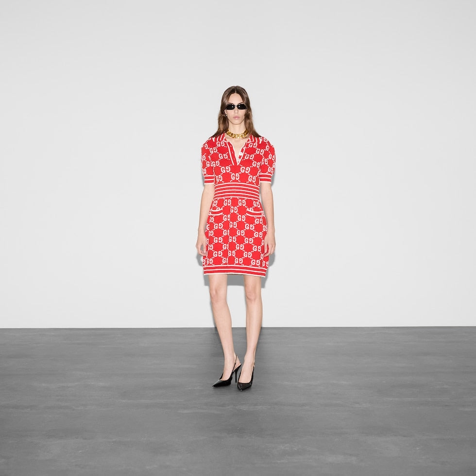 Woman wearing a red patterned dress standing against a plain background