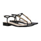 Black sandals with gold chain detail on a light gray background